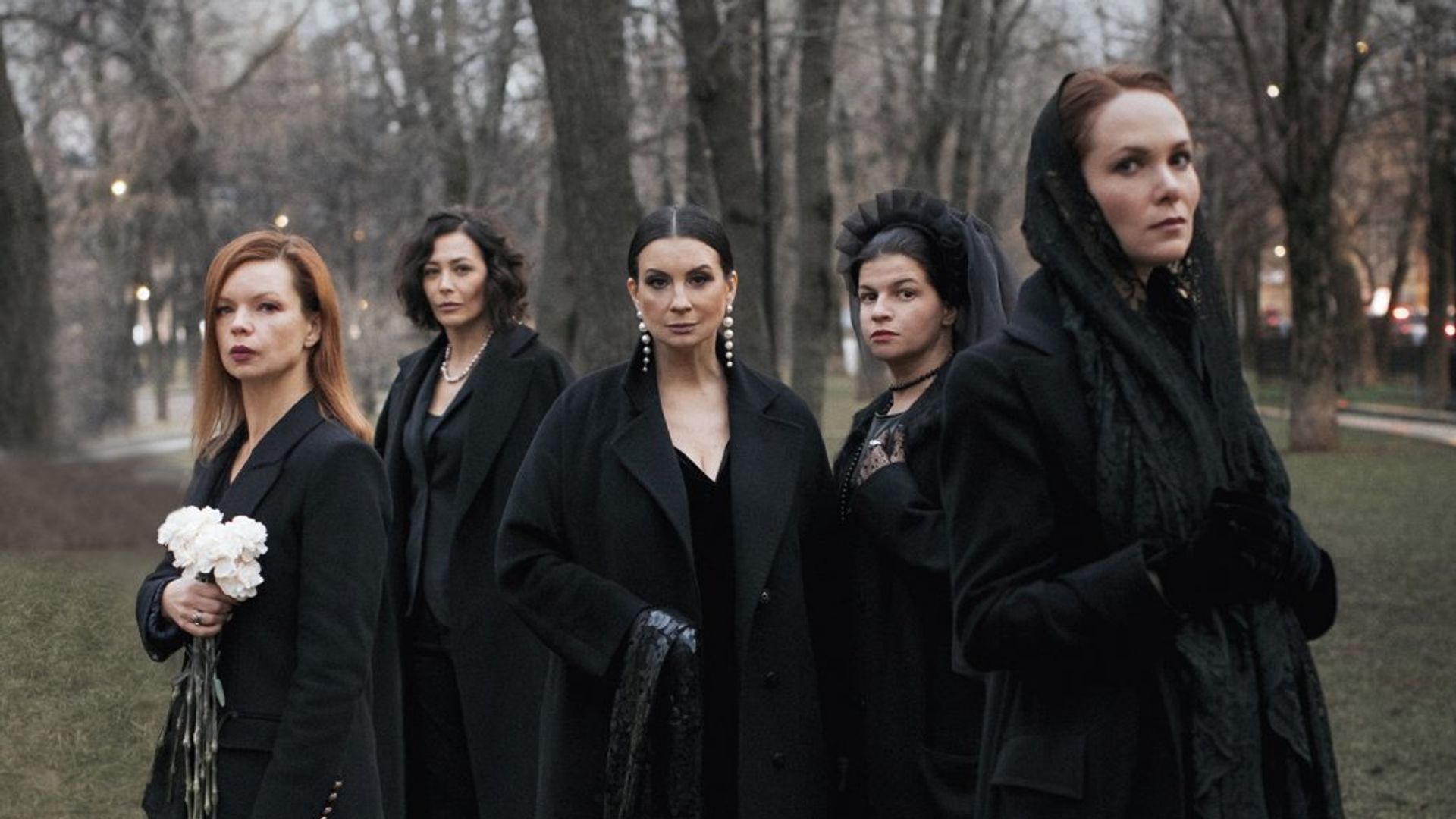 Пять женщин в чёрных нарядах стоят в парке