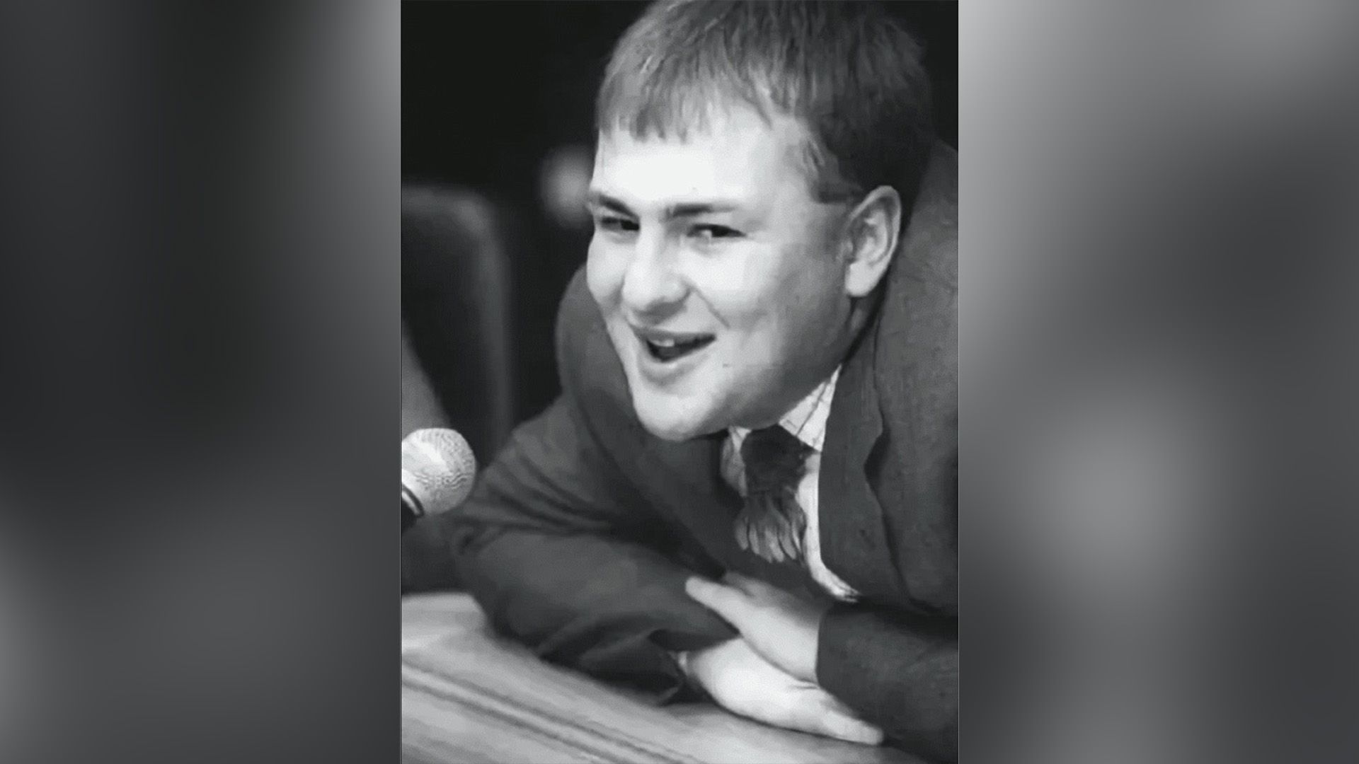 Андрей Мельниченко в пиджаке и галстуке облокотился на стол